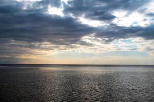 lindo pôr do sol sobre mar com reflexão dentro água, majestoso nuvens dentro a céu. marinha foto