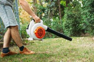 sem fio folha sopradores. portátil, sem fio, elétrico folha ventilador dentro uma jardim, seletivo foco. outono, outono jardinagem trabalho dentro uma quintal, em uma grama, grama. jardim funciona. foto