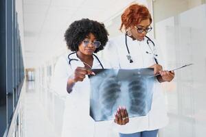 africano médicos olhando às pacientes raio X às hospital foto