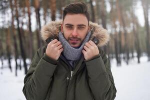 atraente barbudo homem em pé ao ar livre dentro inverno estação floresta. foto