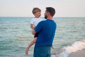 pai filho gastos Tempo juntos mar período de férias jovem Papai criança pequeno Garoto caminhando de praia foto