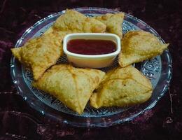 samosas com tomate molho dentro a prato - alo samosa com vermelho molho picante - samosa com ketchup foto