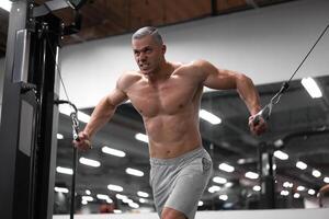 muscular Atlético fisiculturista em pé Treinamento peito e ombros músculos em ginástica equipamento foto