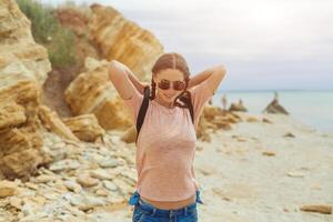 uma hipster menina com trançado cabelo dentro tranças é caminhando ao longo a de praia dentro roupas. verão conceito, lazer turismo foto