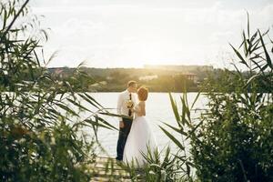 elegante □ Gentil à moda noivo e noiva perto rio ou lago. Casamento casal dentro amor foto