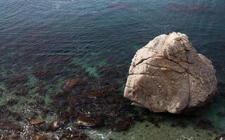grande pedra dentro a transparente mar água foto