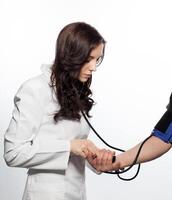 uma mulher dentro uma branco casaco é verificação sangue pressão foto