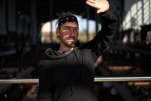 bonito jovem com a barba por fazer homem Preto moletom com capuz e bandana carrinhos foto