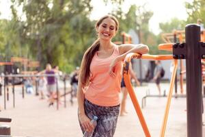 esportivo mulher em pé verão dia em esporte terra em repouso depois de Difícil Treinamento beber água plástico garrafa médio tiro foto