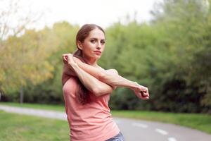 mulher corredor alongamento braços antes corrida verão parque foto