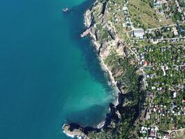 aéreo Visão a partir de acima em calma azul mar e vulcânico rochoso margens. pequeno ondas em água superfície dentro movimento borrão. natureza verão oceano mar de praia fundo. ninguém. feriado, período de férias e viagem conceito foto