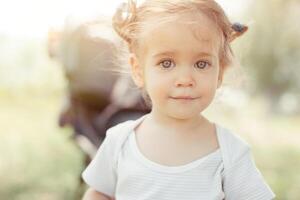 bebê menina em pé perto uma bebê transporte foto