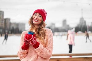 lindo adorável meia idade menina com encaracolado cabelo caloroso inverno suéter carrinhos gelo rinque fundo Cidade quadrado. foto