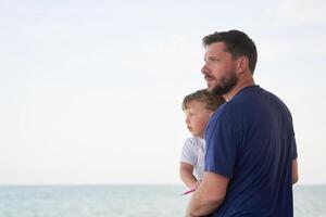 pai filho gastos Tempo juntos mar período de férias jovem Papai criança pequeno Garoto caminhando de praia foto