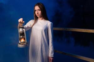 misterioso místico menina dentro uma Sombrio noite floresta com uma querosene luminária dentro dela mãos foto