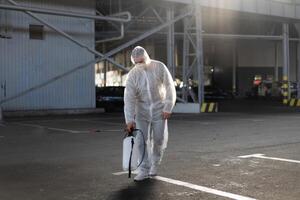 homem vestido branco protetora macacão pulverização superfície antibacteriano desinfetante pulverizador durante quarentena foto