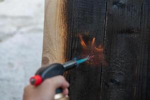 profissional carpinteiro usando velho tradicional japonês técnica. queimando madeira pranchas com gás queimador foto