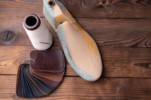 couro amostras para sapatos e plástico sapato último em Sombrio de madeira mesa. foto