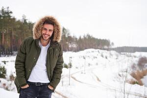 atraente barbudo homem em pé ao ar livre dentro inverno estação floresta. foto