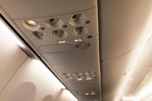 a sobrecarga console dentro a moderno passageiro aeronaves. ar condicionador botão e iluminação interruptor foto