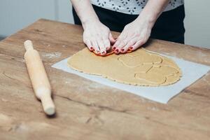 fechar acima do fêmea mãos fazer biscoitos a partir de fresco massa às casa foto