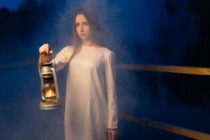 misterioso místico menina dentro uma Sombrio noite floresta com uma querosene luminária dentro dela mãos foto