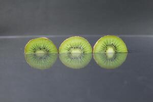 dois ou três círculos do verde kiwi semicírculo com uma Preto lustroso ainda vida foto