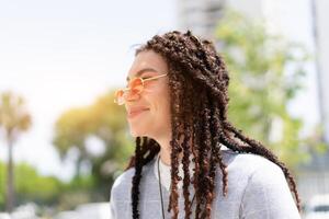 mulheres hipster com tranças e Rosa oculos de sol retrato ao ar livre lado visualizar. fechar acima Tiros na Cabeça moderno na moda fêmea foto