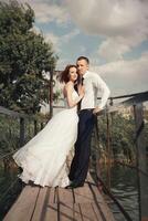 Casamento casal caminhando em ponte perto lago em pôr do sol às Casamento dia. noiva e noivo dentro amor foto