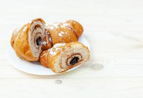 fresco croissant com chocolate em a branco de madeira fundo foto