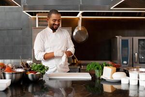 jovem atraente masculino cozinhar golpes acima dele protetora luva piadas e tem Diversão dentro a profissional cozinha foto