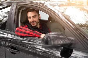 jovem atraente caucasiano homem senta às a roda do dele carro ensolarado inverno dia. foto