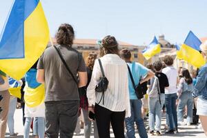 Portugal, Lisboa abril 2022 a demonstração em comércio quadrado dentro Apoio, suporte do Ucrânia e contra a russo agressão. manifestantes contra da rússia guerra muitos pessoas com ucraniano bandeiras. foto