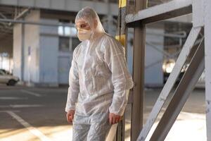 desespero cuidados de saúde trabalhador dentro branco cobiçado protetora macacão. cansado masculino caucasiano médico dentro depressão durante coronavírus pandemia foto