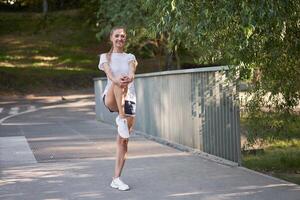 mulher corredor alongamento pernas antes exercício verão parque manhã foto