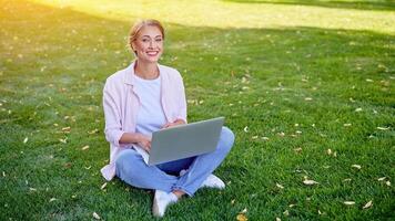 empresária sentado Relva verão parque usando computador portátil o negócio persone trabalhando controlo remoto. ao ar livre foto