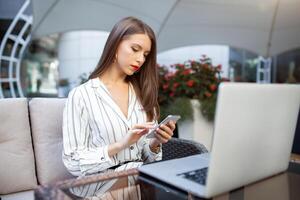 ao ar livre retrato do caucasiano empresária usando sem fio Internet conexão em computador portátil e gadgets, Mensagens através da popular social redes, vestido casualmente. pessoas e tecnologia conceito foto