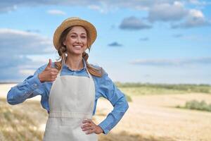 mulher agricultor Palha chapéu avental em pé terras agrícolas sorridente fêmea agrônomo especialista agricultura agronegócio feliz positivo caucasiano trabalhador agrícola campo foto