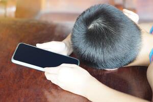 não identificado Garoto enfrentou baixa em mesa, dormindo durante detém Smartphone. conceito, Smartphone viciado para jogar jogos ou social meios de comunicação. triste, depressão a partir de cyberbullying foto