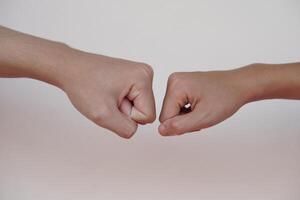 fechar acima dois mãos colisão seus punhos juntos para saudações. conceito, corpo linguagem. mãos gesto símbolo para saudações, dando respeito ou aprovação Como companhia entre dois pessoas. foto