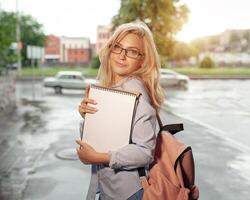 entusiasmado feliz lindo jovem menina sorriso gand segurando pilha do livros em pé perto campus estilo de vida positividade acadêmico graduando universidade escola foto