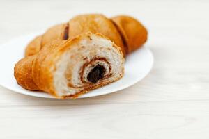 fresco croissant com chocolate em a branco de madeira fundo foto