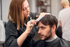 bonito azul olhos homem sentado dentro barbeiro fazer compras. estilista de cabelo cabeleireiro mulher corte dele cabelo. fêmea barbeiro. foto