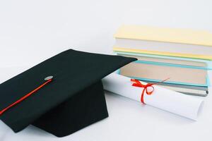 uma Preto quadrado graduado chapéu com uma vermelho pendão mentiras em uma diploma e uma pilha do livros. Educação conceito foto