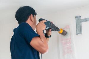 técnico homem perfuração para concreto parede com testemunho broca máquina para instalar moderno ar condicionador, manutenção e manutenção conceitos foto