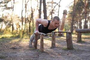 bonito caucasiano homem empurrar acima ao ar livre exercite-se Cruz Treinamento manhã bombeamento tríceps braço exercício Esportes terra foto