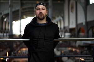 bonito jovem com a barba por fazer homem Preto moletom com capuz e bandana carrinhos foto