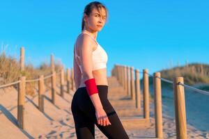 Atlético mulher retrato ar livre. caucasiano fêmea esportivo mulher em pé em natureza oceano de praia foto