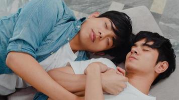 jovem casal gay asiático dorme juntos em casa. adolescentes coreanos lgbtq homens felizes relaxar descansar deitado na cama no quarto em casa pela manhã. foto