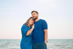 homem abraçando mulher em pé mar de praia. romântico relação em verão período de férias foto